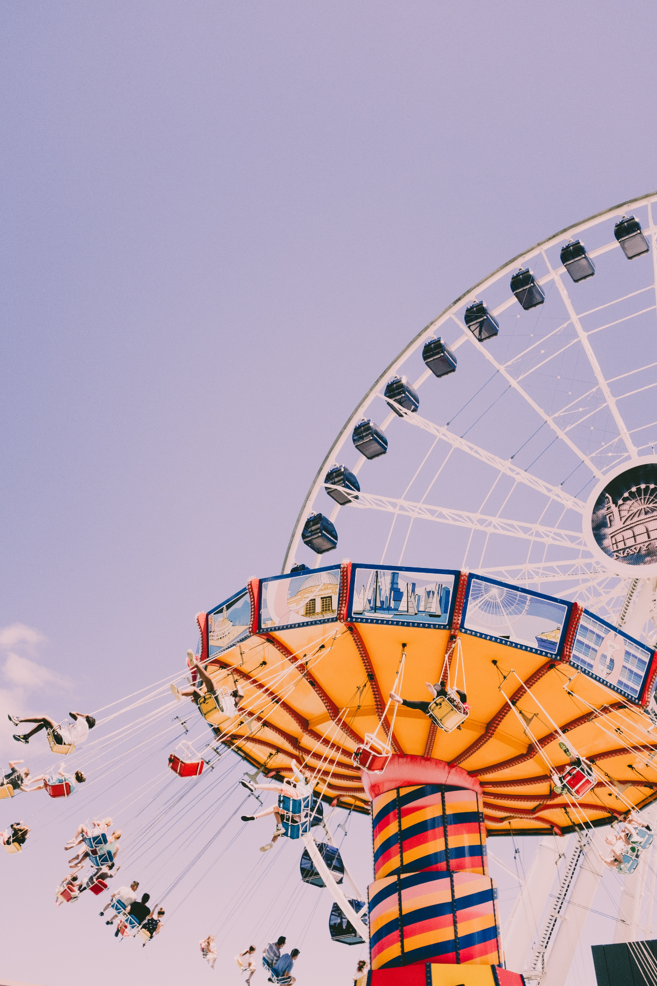 Manège à chaînes volantes et grande roue à la kermesse sous un ciel pastel
